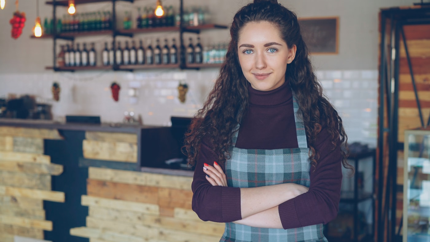 Cafe owner standing confidently behind a small-business counter
